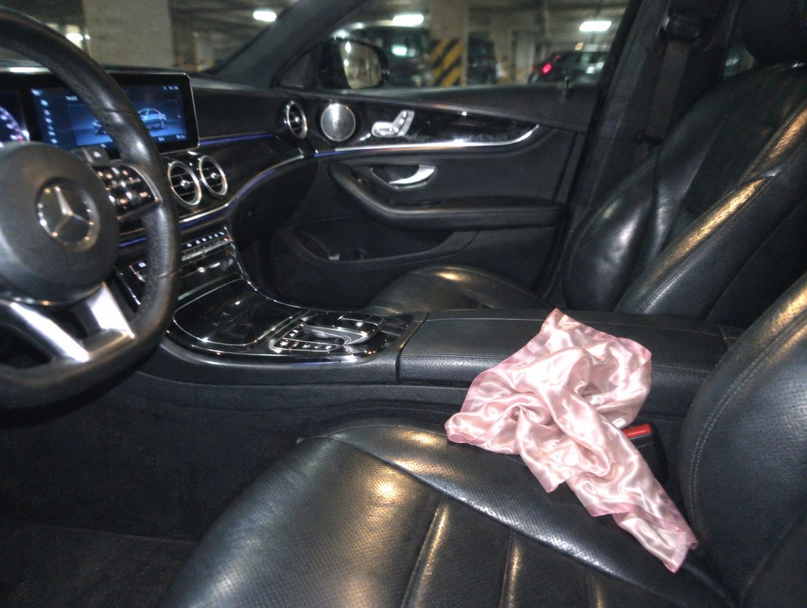 A pink scarf on the passenger seat of a Mercedes